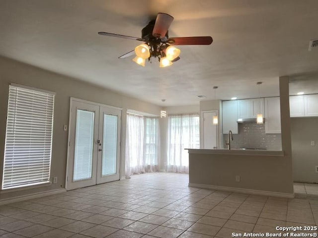 unfurnished living room featuring a sink, baseboards, ceiling fan, and french doors