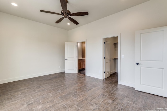 unfurnished bedroom with wood finished floors, baseboards, connected bathroom, a spacious closet, and recessed lighting