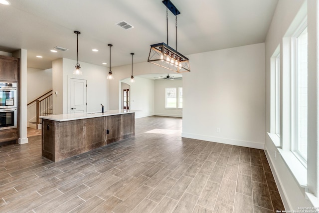 kitchen with stainless steel double oven, a ceiling fan, open floor plan, and visible vents