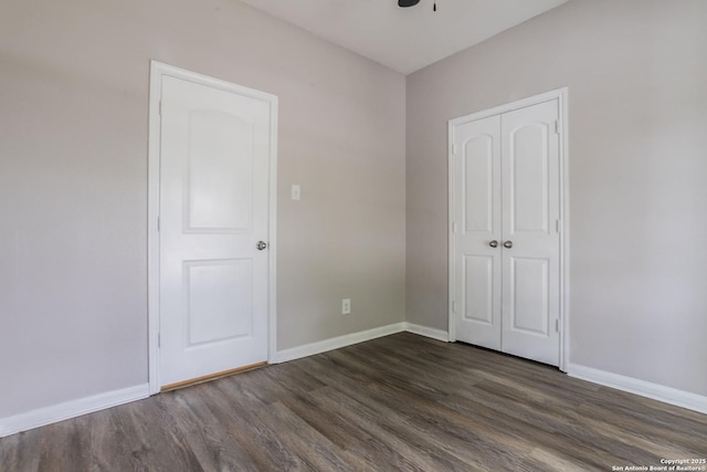 unfurnished bedroom featuring baseboards, a ceiling fan, a closet, and dark wood-style flooring