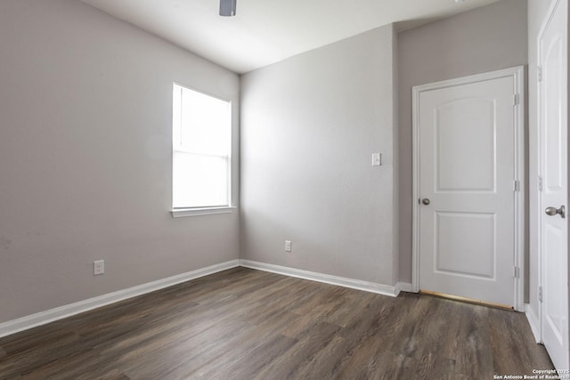 spare room featuring baseboards, a ceiling fan, and dark wood finished floors