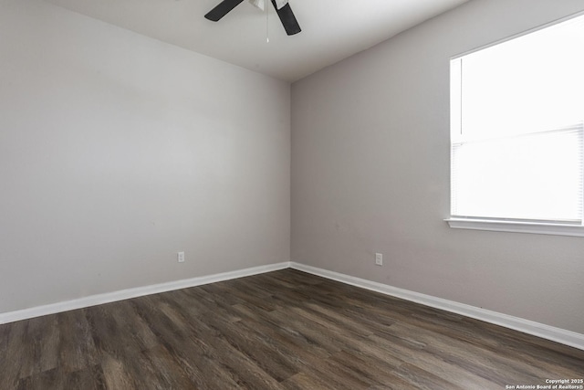 spare room with baseboards, a ceiling fan, and dark wood-type flooring