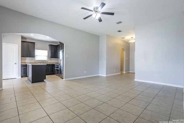 unfurnished living room with arched walkways, a ceiling fan, baseboards, light tile patterned floors, and visible vents