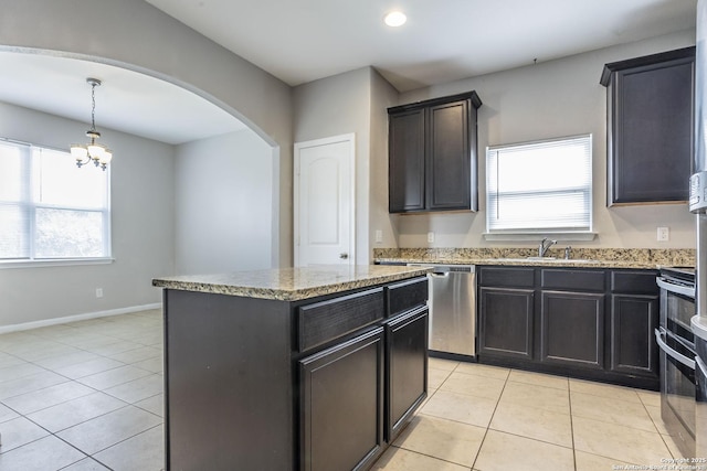 kitchen featuring arched walkways, light stone countertops, a sink, and light tile patterned flooring