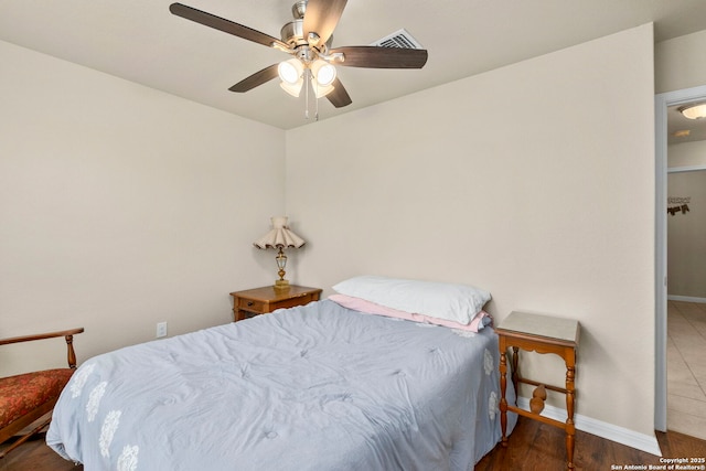 bedroom with visible vents, baseboards, ceiling fan, and wood finished floors
