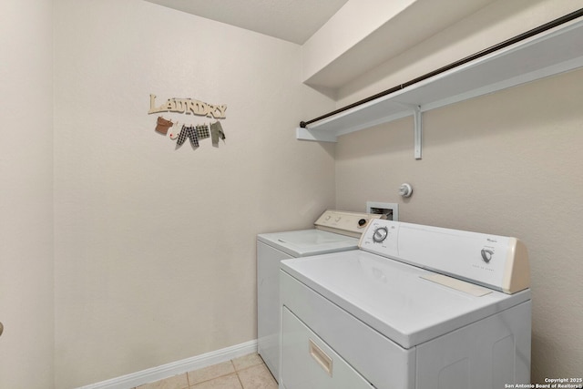 clothes washing area with laundry area, washer and clothes dryer, baseboards, and light tile patterned floors