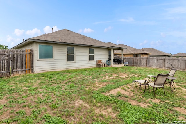 rear view of house with a lawn, a fenced backyard, and a patio area