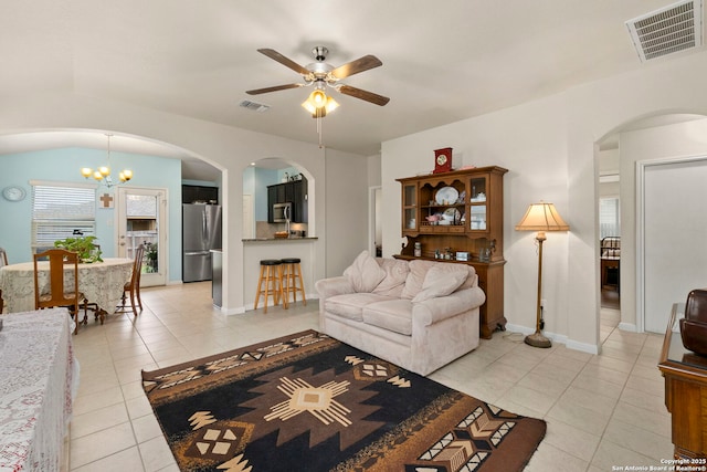 living room featuring light tile patterned floors, ceiling fan with notable chandelier, and visible vents