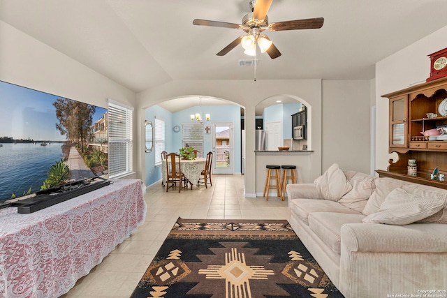 living room featuring baseboards, arched walkways, ceiling fan with notable chandelier, and light tile patterned floors