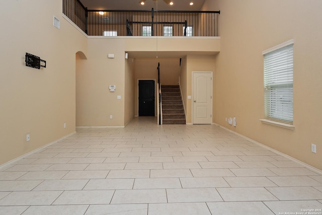 1843 Gray Fox, San Antonio, TX 78245 - unfurnished living room with baseboards, arched walkways, stairs, and a towering ceiling
