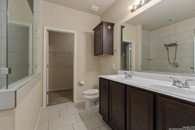 1843 Gray Fox, San Antonio, TX 78245 - bathroom featuring a tile shower, a sink, a walk in closet, toilet, and tile patterned floors