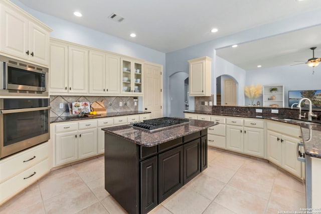 kitchen with a sink, arched walkways, backsplash, and stainless steel appliances