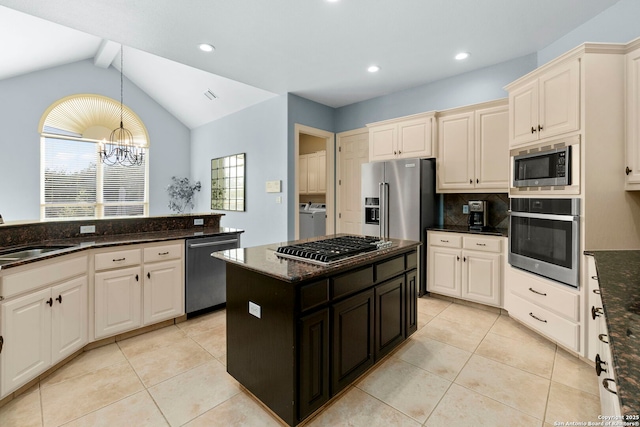 kitchen with hanging light fixtures, a sink, stainless steel appliances, tasteful backsplash, and washer and clothes dryer