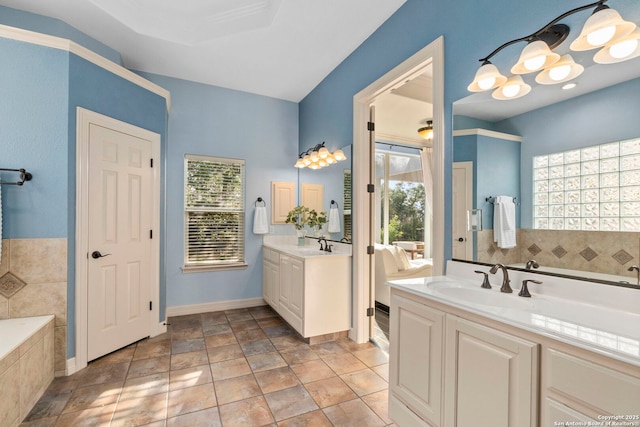 bathroom with baseboards, a sink, a bath, and two vanities