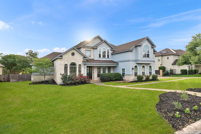 view of front of house with stucco siding, a front lawn, and fence