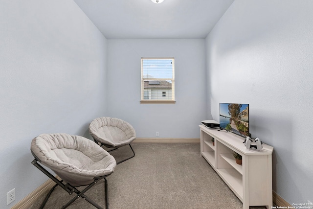 sitting room with baseboards and light colored carpet