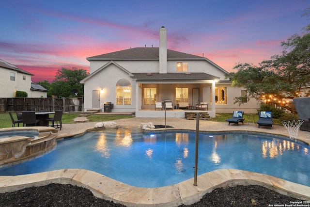 view of pool with a patio, fence, and a pool with connected hot tub