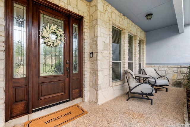 doorway to property with covered porch and stone siding