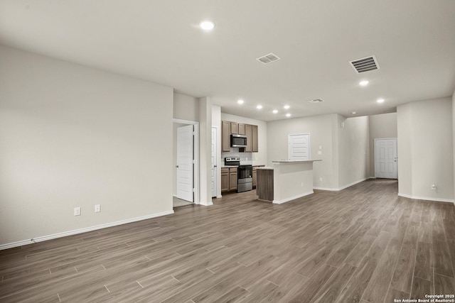 unfurnished living room with visible vents, recessed lighting, baseboards, and wood finished floors