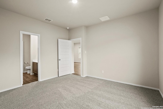 unfurnished bedroom featuring visible vents, carpet flooring, baseboards, and ensuite bath