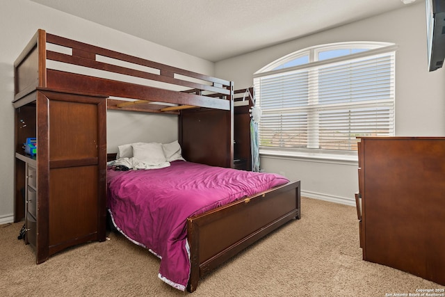 bedroom featuring baseboards, multiple windows, and light carpet
