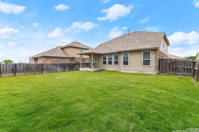 rear view of property featuring a fenced backyard, a lawn, a patio area, and brick siding