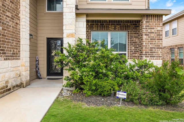 entrance to property featuring brick siding and stone siding