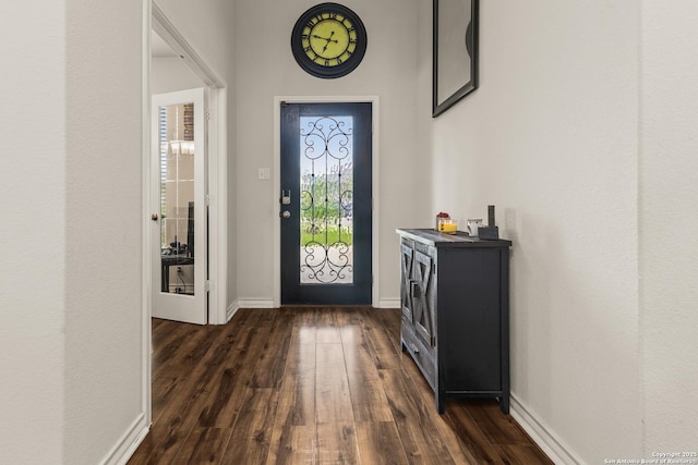 foyer entrance featuring baseboards and dark wood finished floors