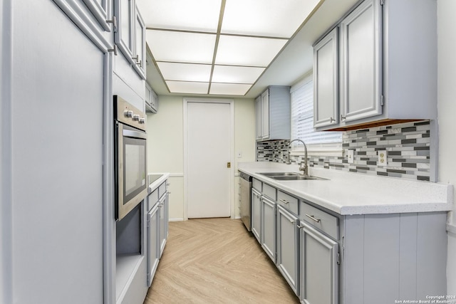 7442 Castle Trail Dr, San Antonio, TX 78218 - kitchen with appliances with stainless steel finishes, a sink, light countertops, gray cabinets, and backsplash