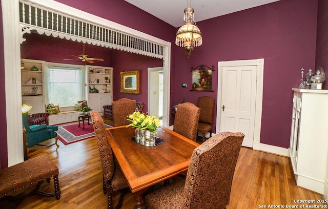 dining space with baseboards, ceiling fan with notable chandelier, and wood finished floors