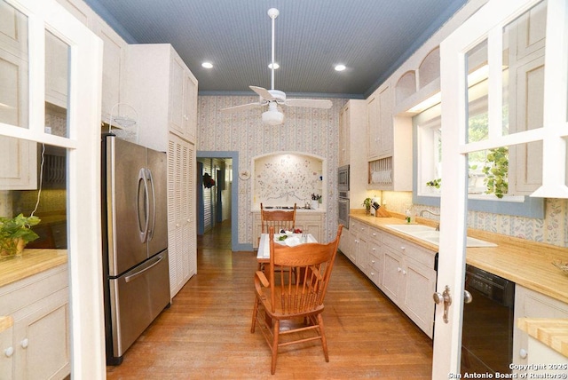 kitchen with a ceiling fan, light countertops, light wood-style floors, stainless steel appliances, and wallpapered walls