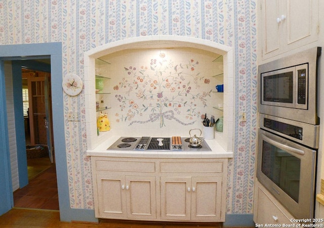 kitchen with appliances with stainless steel finishes, tile counters, and wallpapered walls