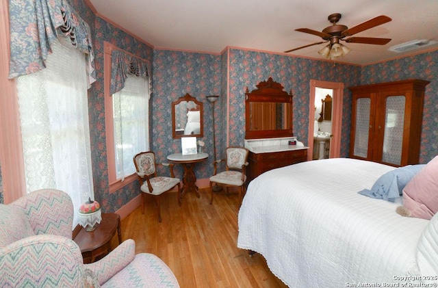 bedroom featuring crown molding, wallpapered walls, wood finished floors, and visible vents