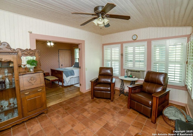 living area featuring tile patterned flooring, ceiling fan, wood walls, and a wealth of natural light