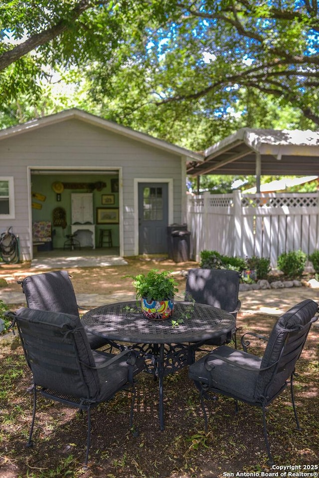 view of patio with outdoor dining area, an outdoor structure, and fence
