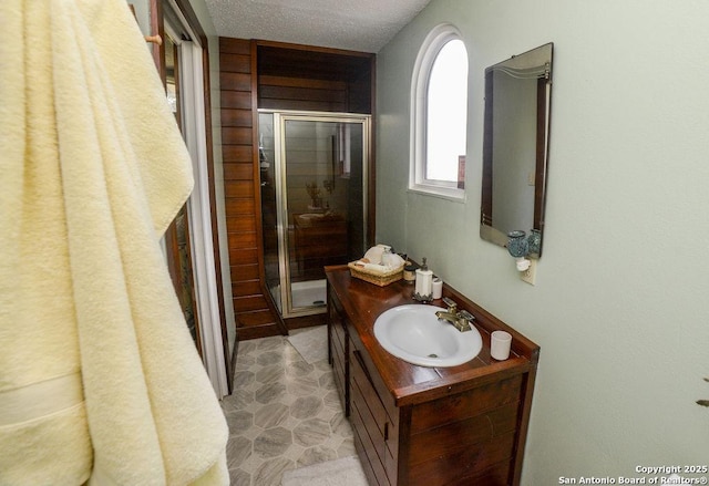 bathroom with vanity, a textured ceiling, and a stall shower