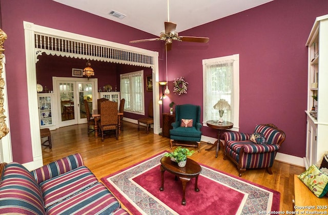 living room featuring visible vents, wood finished floors, baseboards, french doors, and a ceiling fan
