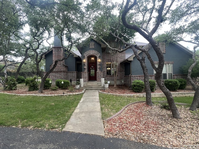 tudor home featuring brick siding and a front yard