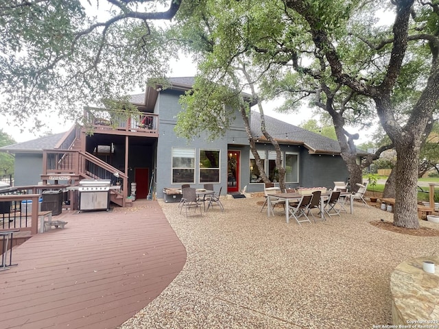 back of house with stairway, stucco siding, a deck, and outdoor dining space