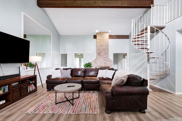 living area with decorative columns, high vaulted ceiling, wood finished floors, and stairway