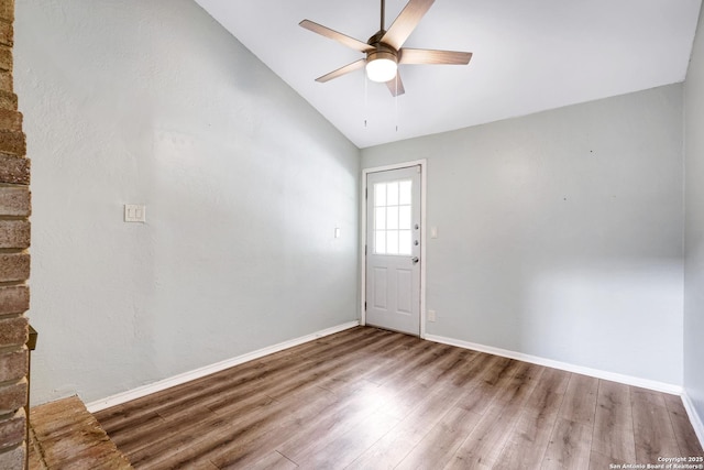 spare room with baseboards, ceiling fan, vaulted ceiling, and wood finished floors