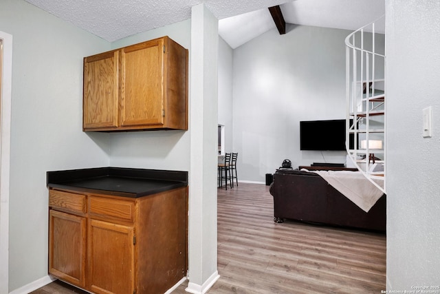 interior space with light wood-type flooring, baseboards, and vaulted ceiling with beams
