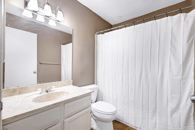 bathroom with vanity, a textured wall, and toilet