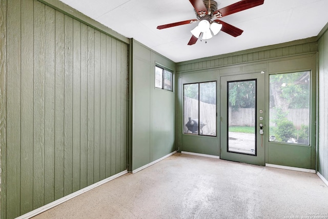spare room featuring baseboards, a ceiling fan, and wooden walls