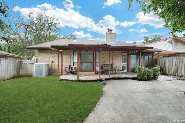 rear view of property featuring a chimney, a wooden deck, central air condition unit, a fenced backyard, and a yard