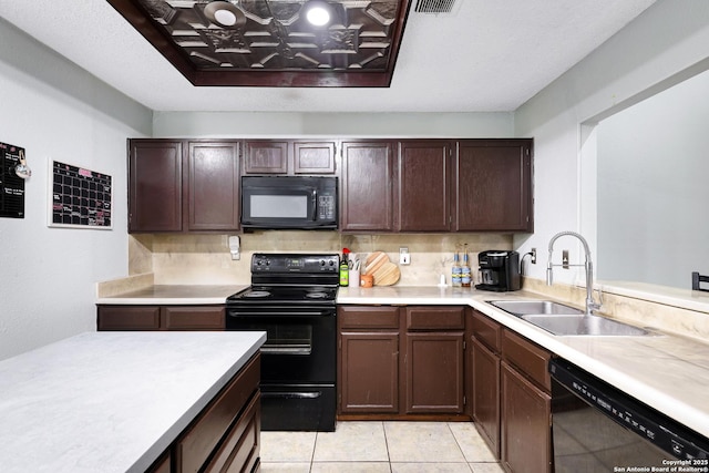 kitchen featuring dark brown cabinets, light countertops, tasteful backsplash, a sink, and black appliances