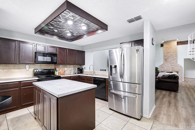 kitchen featuring dark brown cabinets, a sink, light countertops, visible vents, and black appliances