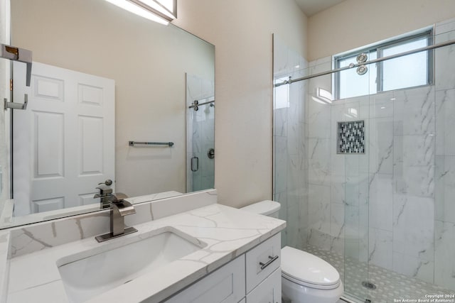 bathroom with toilet, a marble finish shower, and vanity