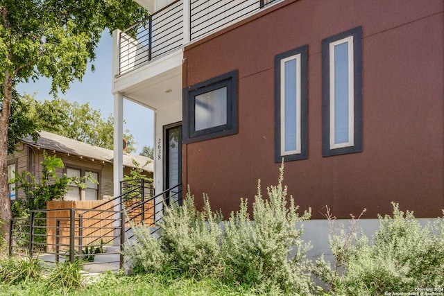 view of property exterior featuring fence, a balcony, and stucco siding