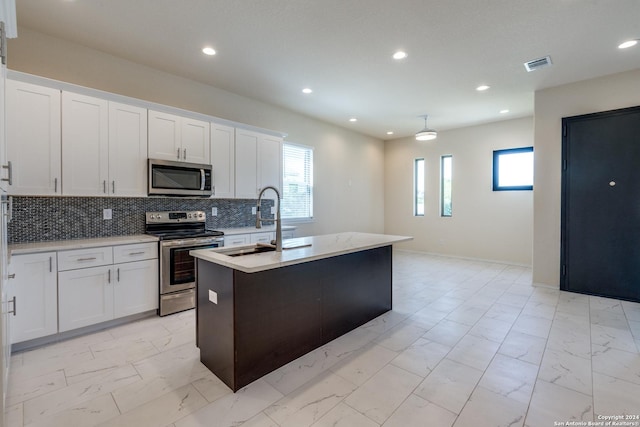 kitchen featuring marble finish floor, light countertops, tasteful backsplash, a sink, and appliances with stainless steel finishes